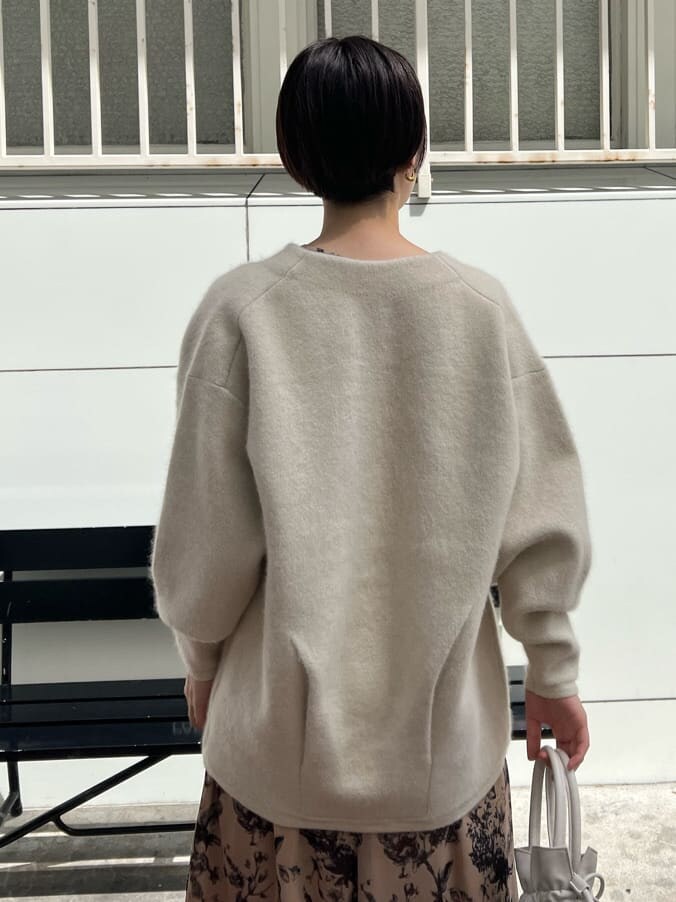 レッド系のブーツ、ホワイト系のカーディガン/ボレロ、ホワイト系のハンドバッグを着用したレディースの秋コーディネートの3枚目の写真