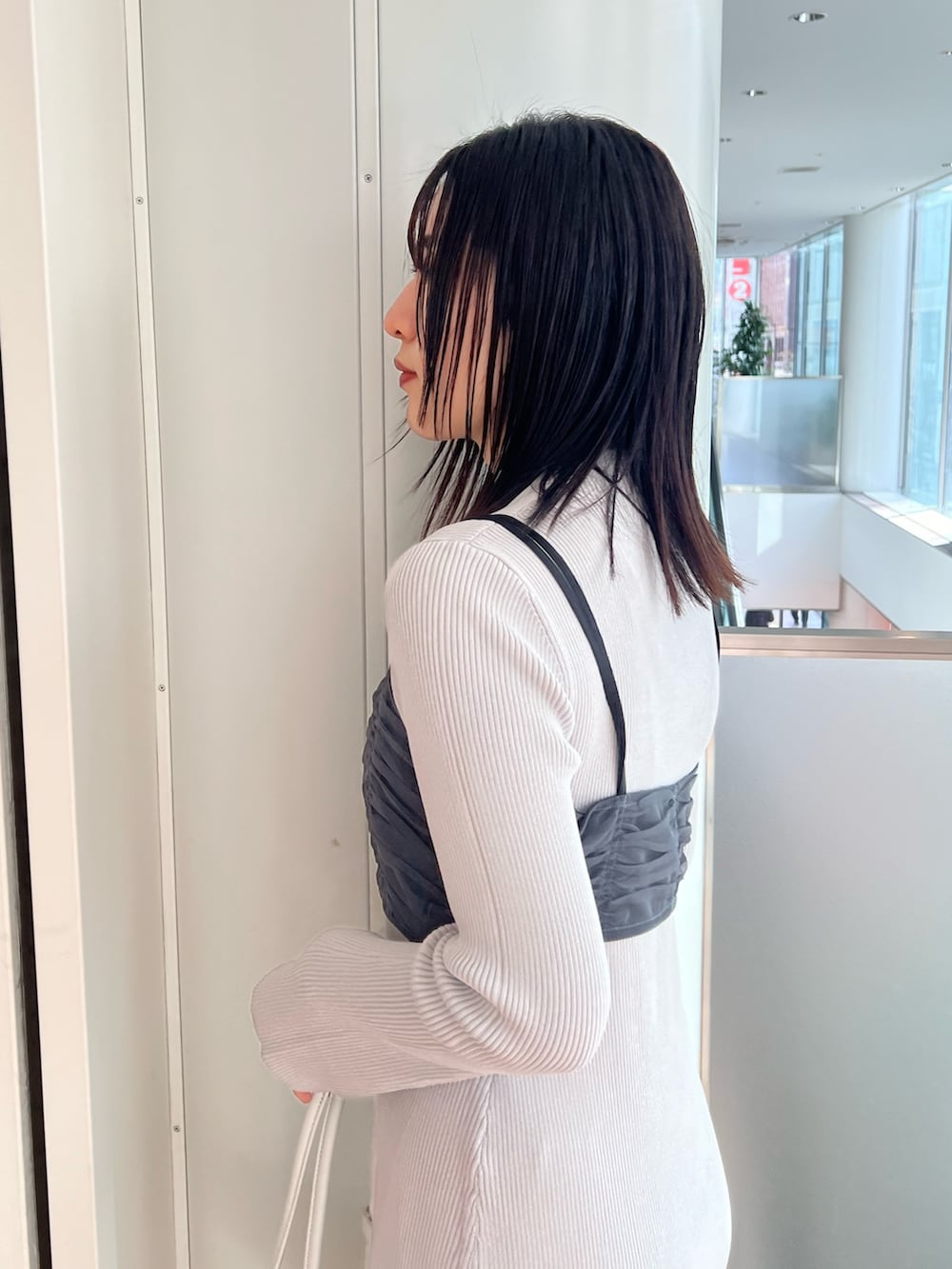 ブラック系のステンカラーコート、ブルー系のワンピース、ブラック系のブーツを着用したレディースの冬コーディネートの7枚目の写真