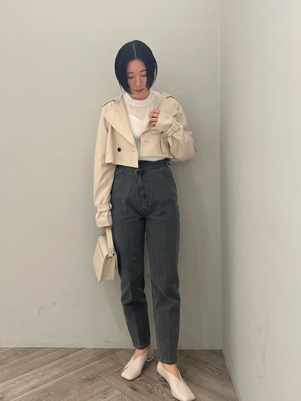 ホワイト系のトレンチコート、ホワイト系のニット/セーター、ブラック系のデニムパンツを着用したレディースの冬コーディネートの4枚目の写真