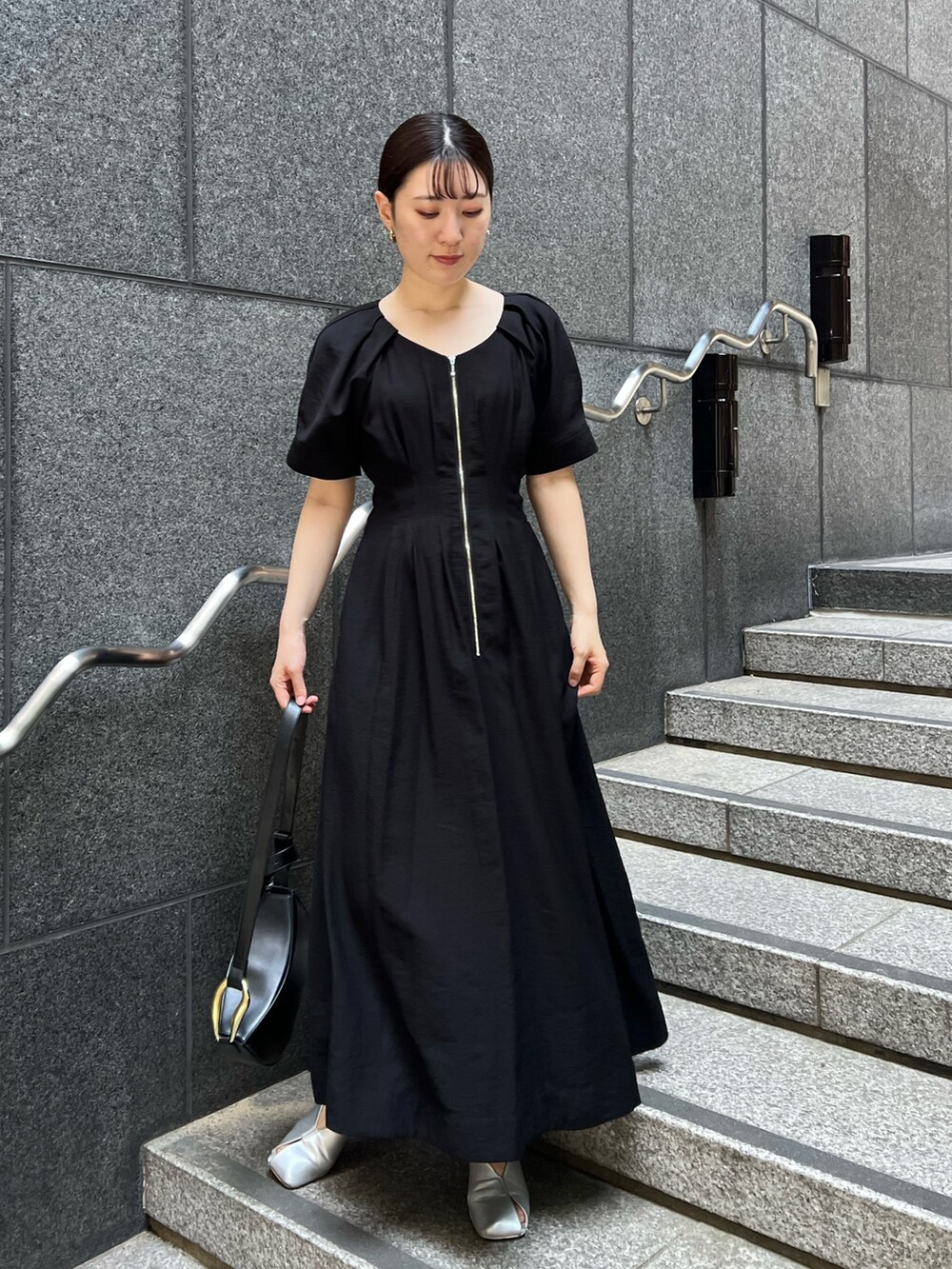 ブラック系のワンピース、ブラック系のショルダーバッグ、シルバー系のパンプスを着用したレディースの夏コーディネートの2枚目の写真