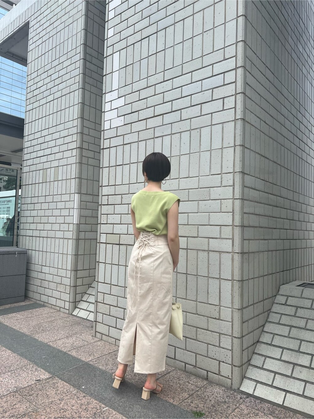 ホワイト系のハンドバッグ、グリーン系のサンダル、ホワイト系のスカートを着用したレディースの春コーディネートの3枚目の写真