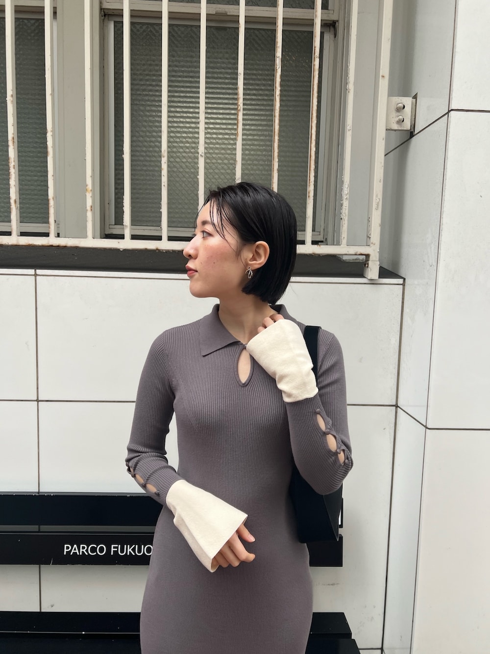 ブラック系のハンドバッグ、グレー系のワンピース、シルバー系のパンプスを着用したレディースの冬コーディネートの3枚目の写真