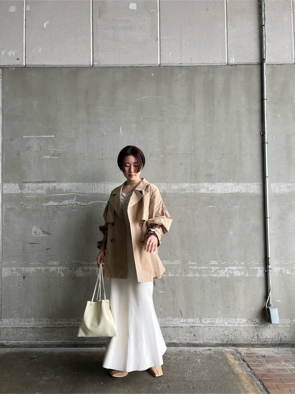 ホワイト系のハンドバッグ、ホワイト系のワンピース、ベージュ系のブーツを着用したレディースの冬コーディネートの2枚目の写真
