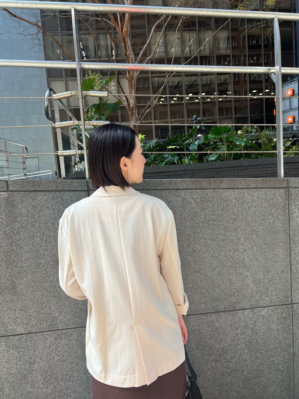 ホワイト系のスニーカー、ブラウン系のワンピース、ブラック系のハンドバッグを着用したレディースの春コーディネートの5枚目の写真