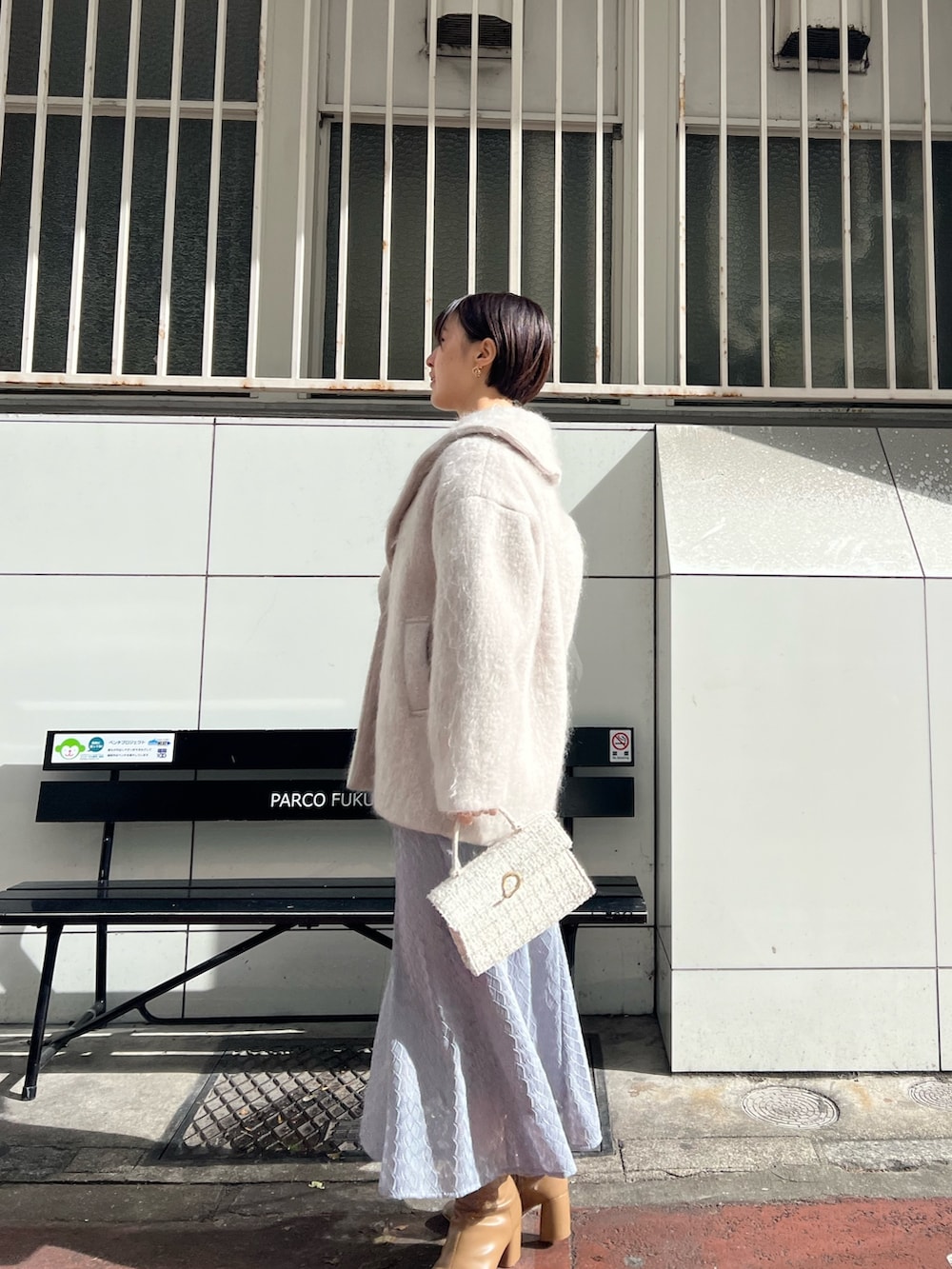 ホワイト系のショルダーバッグ、ベージュ系のブーツ、ベージュ系のその他アウターを着用したレディースの冬コーディネートの2枚目の写真