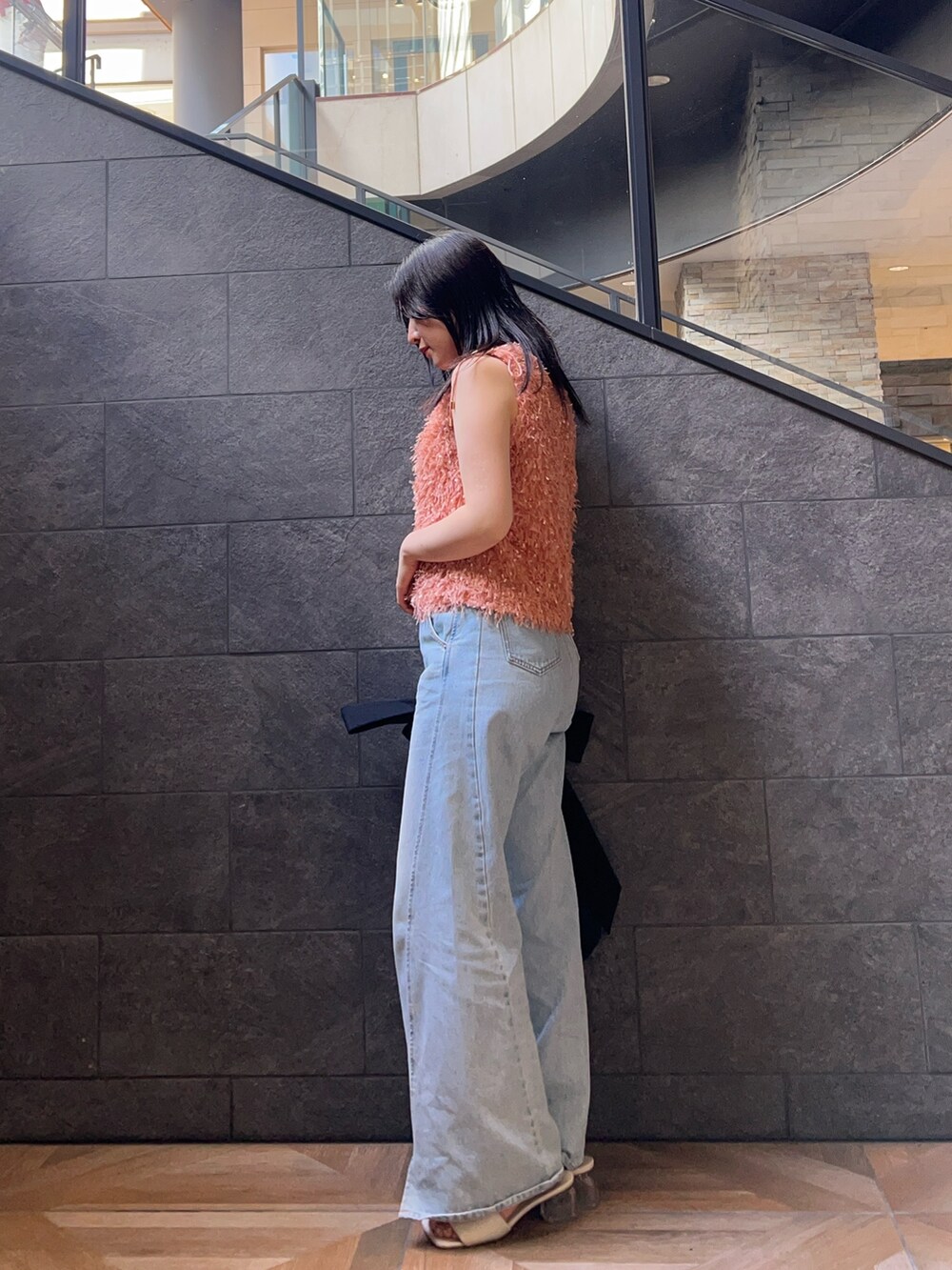 オレンジ系のTシャツ/カットソー、ホワイト系のサンダル、ブルー系のデニムパンツを着用したレディースの夏コーディネートの2枚目の写真