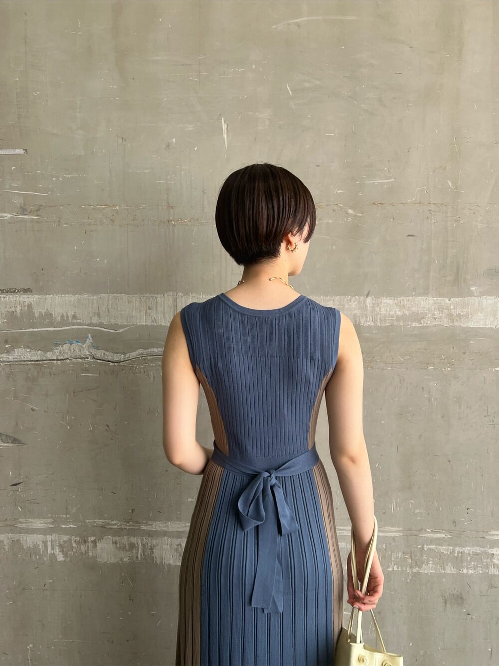 ホワイト系のハンドバッグ、ブルー系のワンピース、ゴールド系のピアス（両耳用）を着用したレディースの夏コーディネートの6枚目の写真