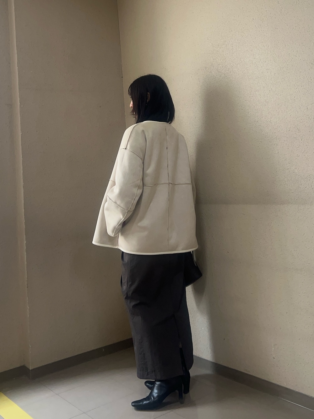 ホワイト系のブルゾン、ブラック系のブーツ、ブラック系のニット/セーターを着用したレディースの秋コーディネートの2枚目の写真