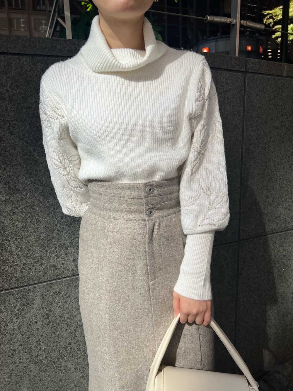 ベージュ系のブーツ、グレー系のスカート、ホワイト系のハンドバッグを着用したレディースの秋コーディネートの7枚目の写真