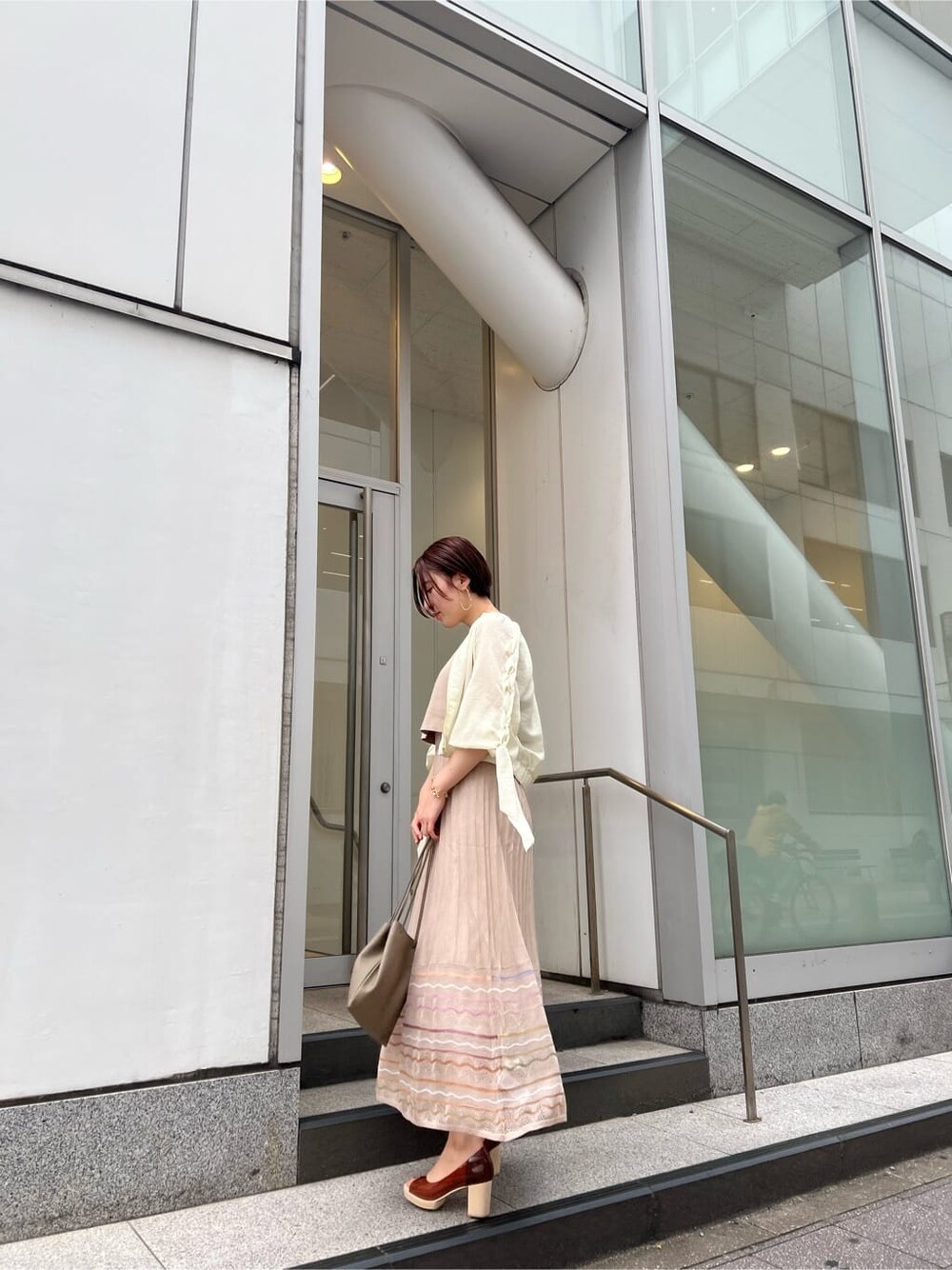 ベージュ系のハンドバッグ、ホワイト系のブルゾン、ベージュ系のワンピースを着用したレディースの春コーディネートの3枚目の写真