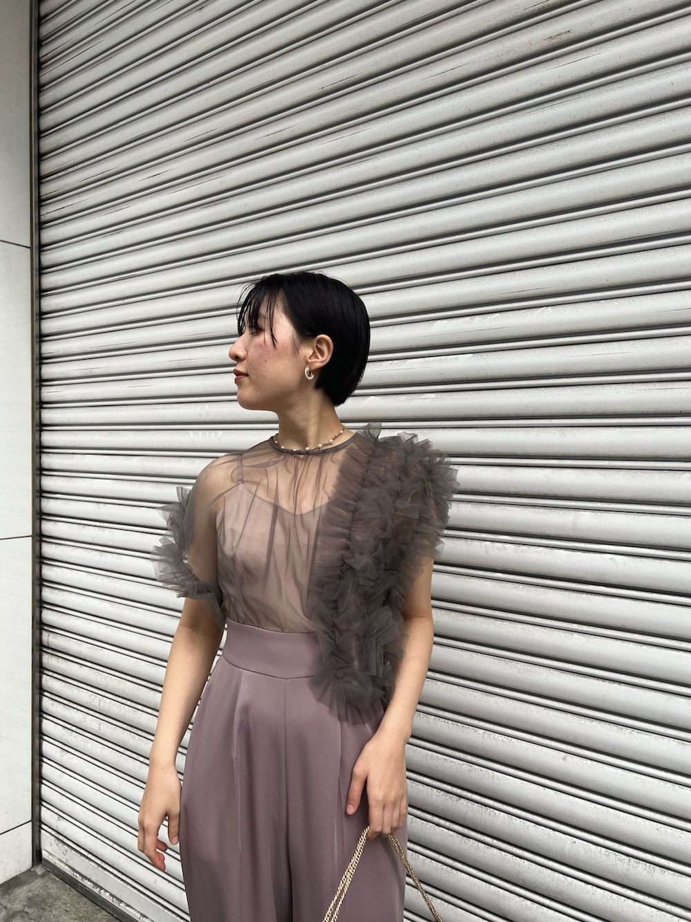 シルバー系のパンプス、ブラック系のチェスターコート、シルバー系のハンドバッグを着用したレディースの冬コーディネートの6枚目の写真