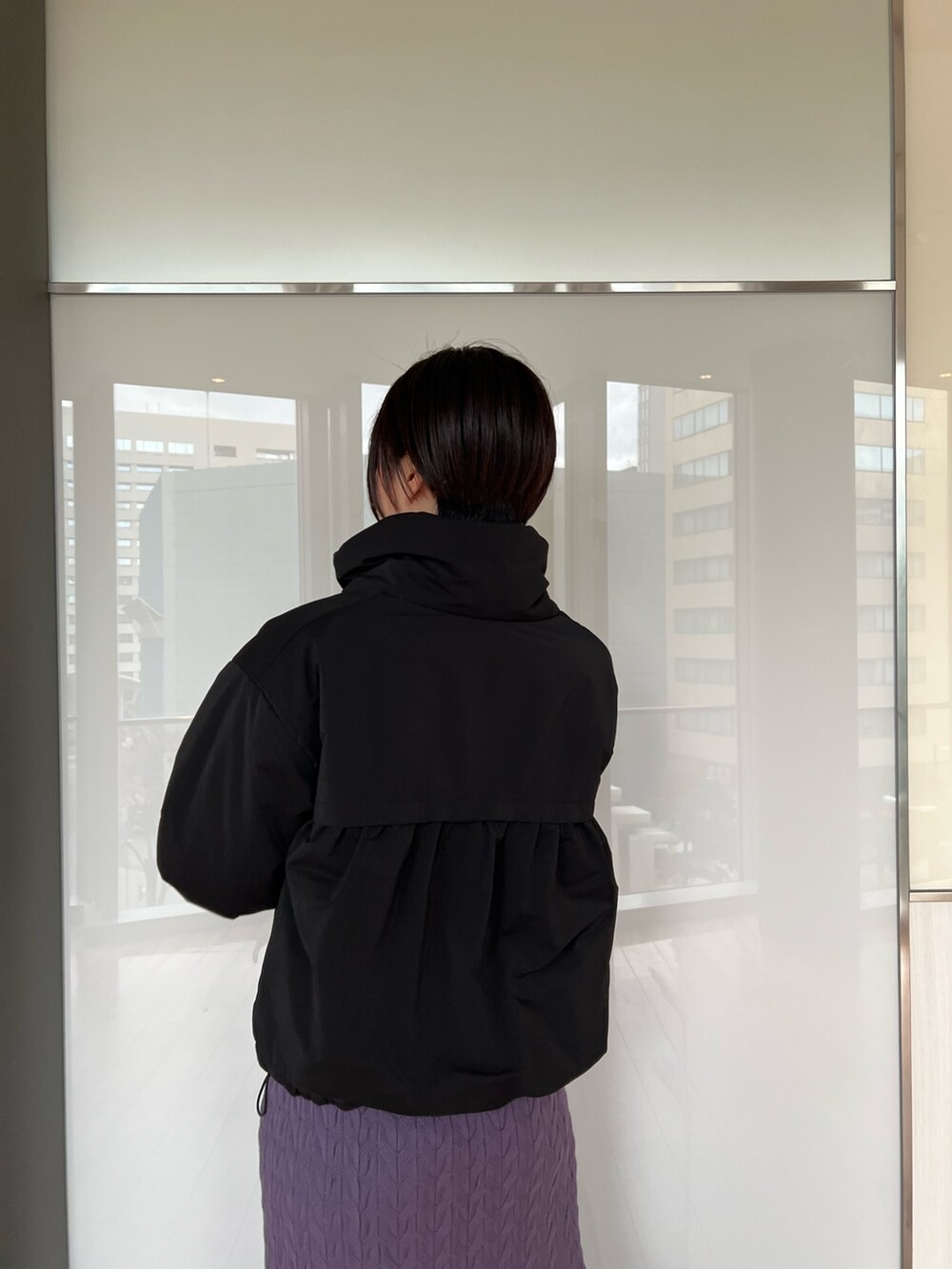 ブラック系のダウンジャケット/コート、ブラック系のブーツ、パープル系のワンピースを着用したレディースの冬コーディネートの6枚目の写真