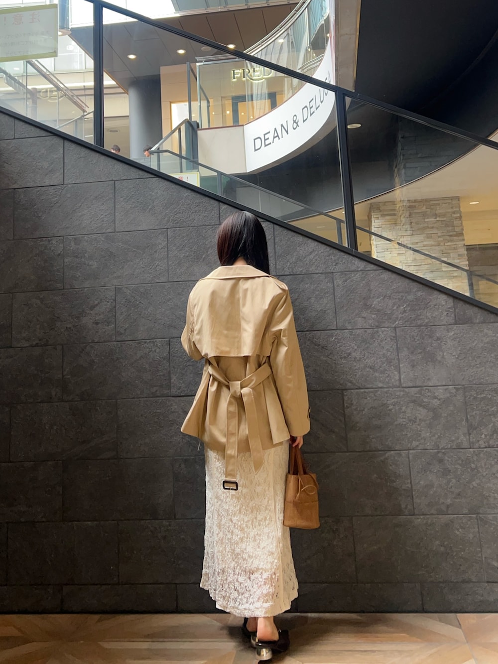 ブラウン系のハンドバッグ、ホワイト系のワンピース、ベージュ系のトレンチコートを着用したレディースの冬コーディネートの3枚目の写真