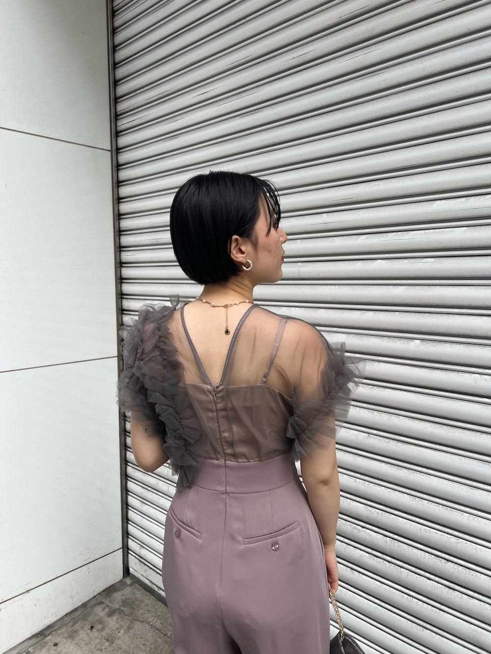 シルバー系のパンプス、ブラック系のチェスターコート、シルバー系のハンドバッグを着用したレディースの冬コーディネートの8枚目の写真