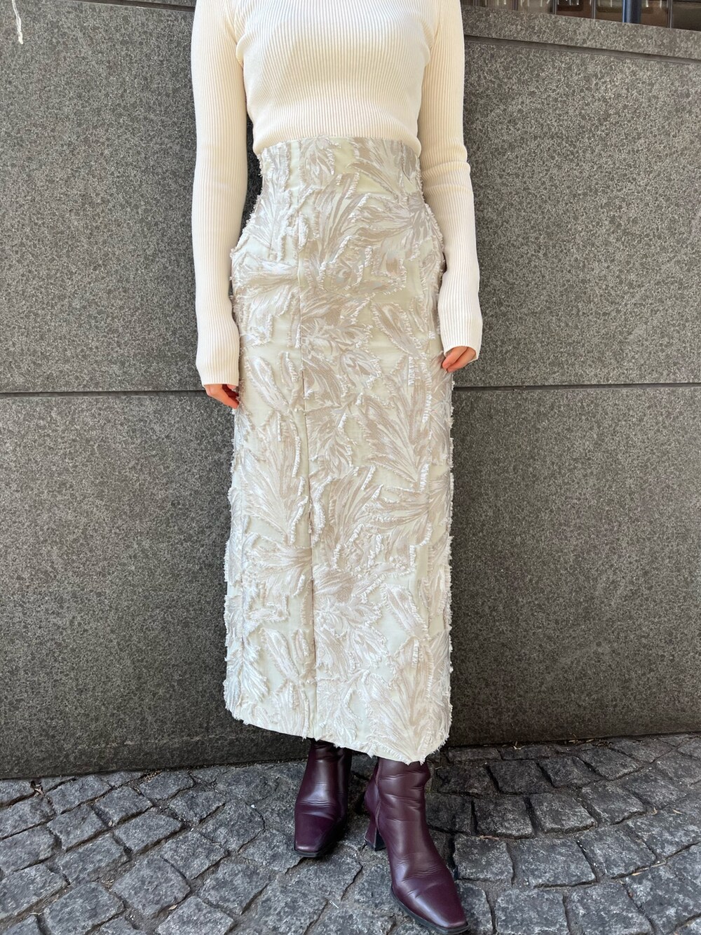 グレー系のカーディガン/ボレロ、ベージュ系のスカート、ホワイト系のニット/セーターを着用したレディースの冬コーディネートの6枚目の写真