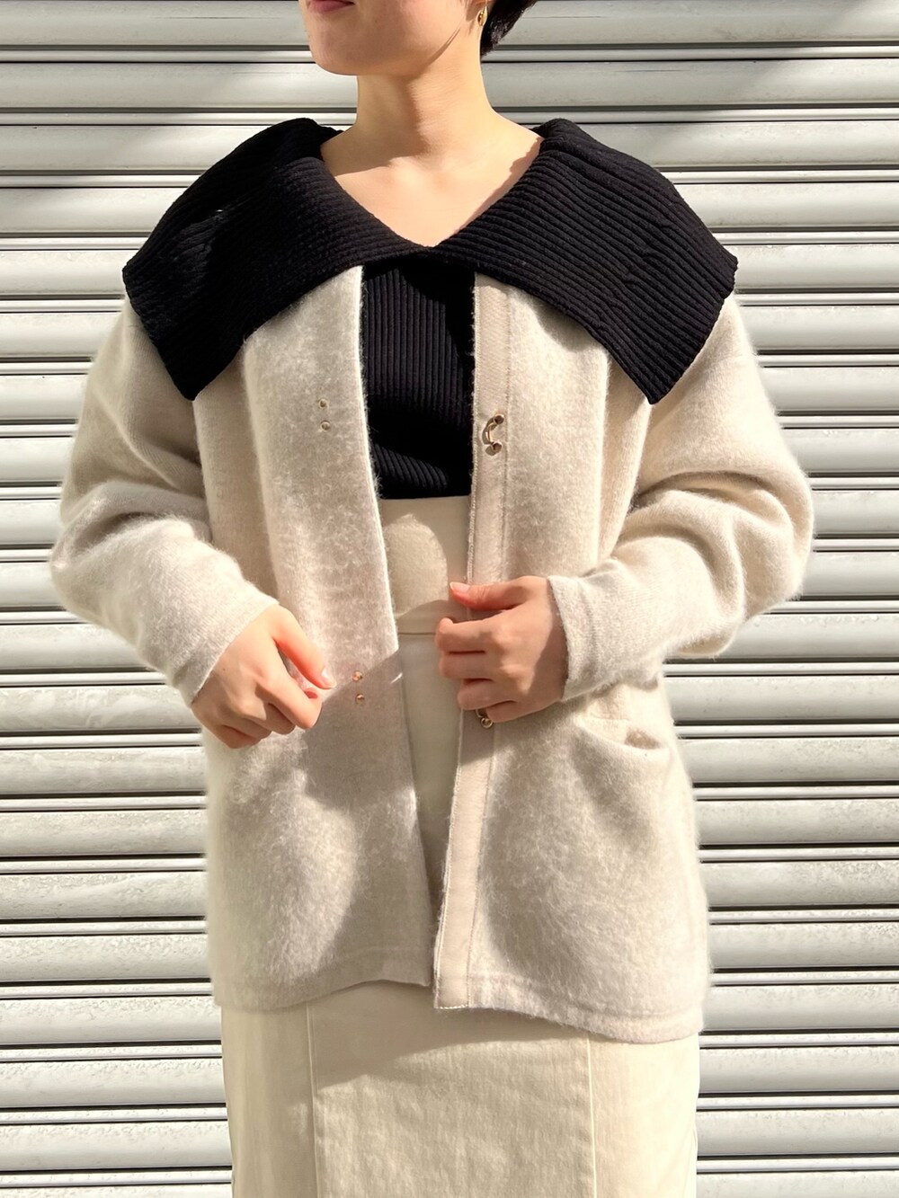 レッド系のブーツ、ホワイト系のスカート、ホワイト系のカーディガン/ボレロを着用したレディースの冬コーディネートの2枚目の写真