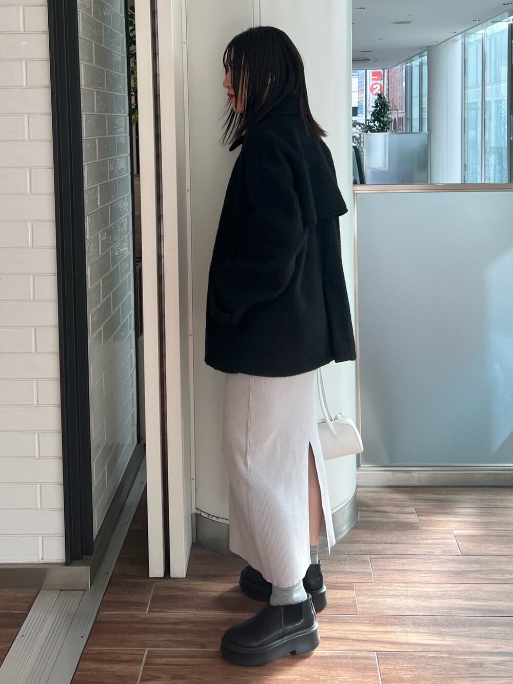 ブラック系のステンカラーコート、ブルー系のワンピース、ブラック系のブーツを着用したレディースの冬コーディネートの2枚目の写真