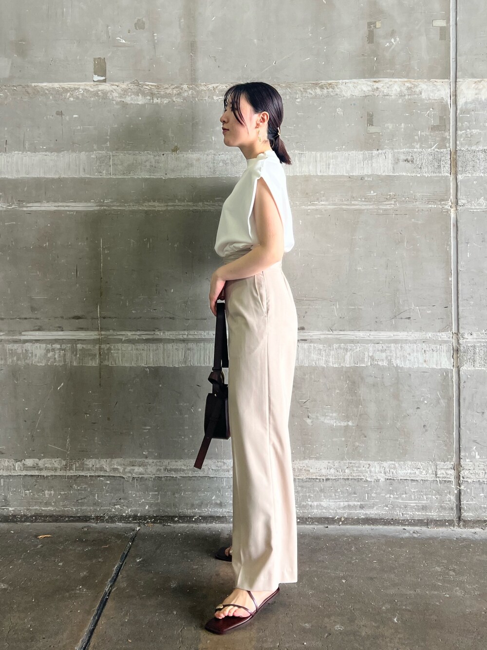 ブラウン系のサンダル、ベージュ系のハンドバッグ、ホワイト系のニット/セーターを着用したレディースの夏コーディネートの2枚目の写真