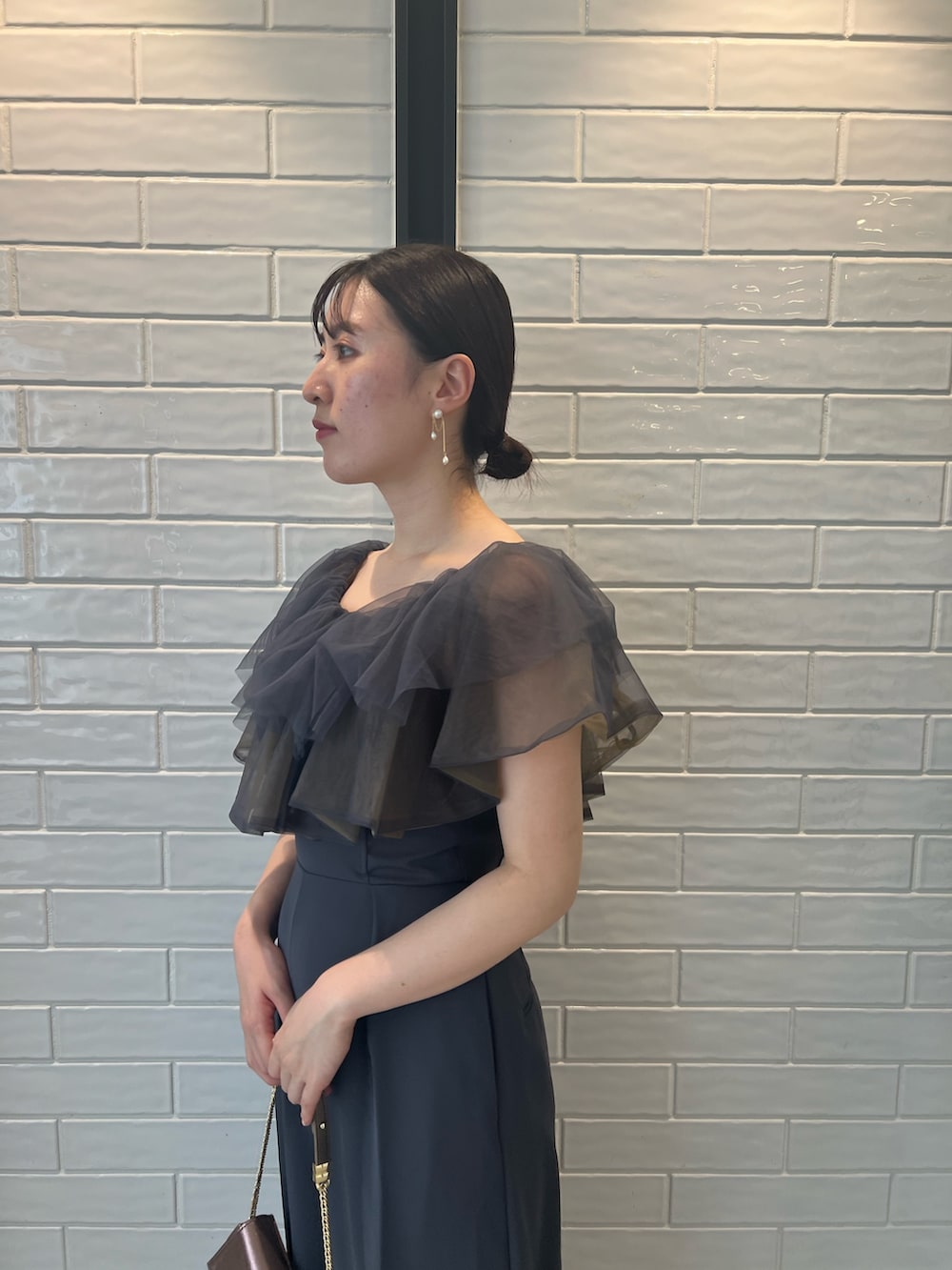 ゴールド系のハンドバッグ、ゴールド系のパンプス、グレー系のパンツドレスを着用したレディースの夏コーディネートの5枚目の写真