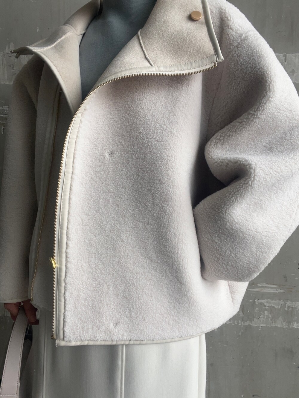 ベージュ系のブーツ、ホワイト系のハンドバッグ、ホワイト系のムートンコートを着用したレディースの秋コーディネートの5枚目の写真