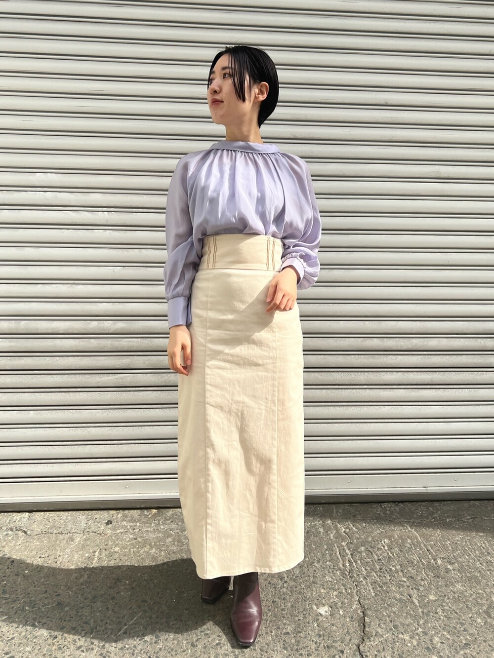 レッド系のブーツ、ホワイト系のスカート、ホワイト系のカーディガン/ボレロを着用したレディースの冬コーディネートの2枚目の写真