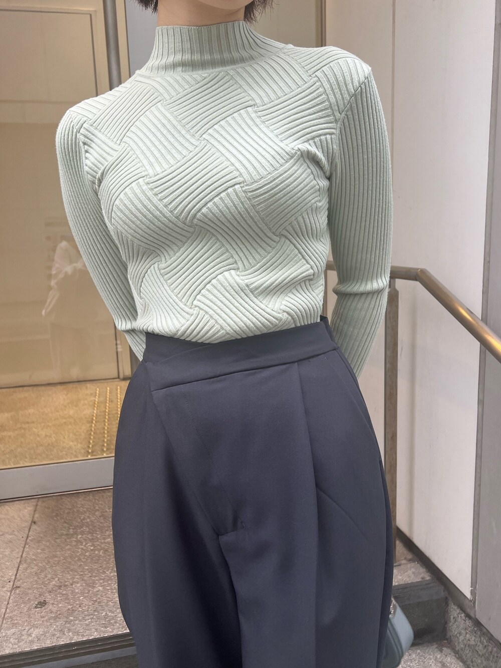 ブルー系のショルダーバッグ、グレー系のスラックス、グリーン系のニット/セーターを着用したレディースの冬コーディネートの6枚目の写真