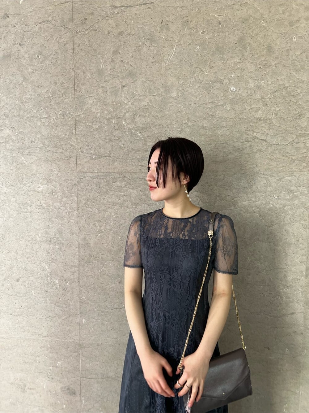 シルバー系のパンプス、グレー系のドレス、シルバー系のクラッチバッグを着用したレディースの冬コーディネートの5枚目の写真