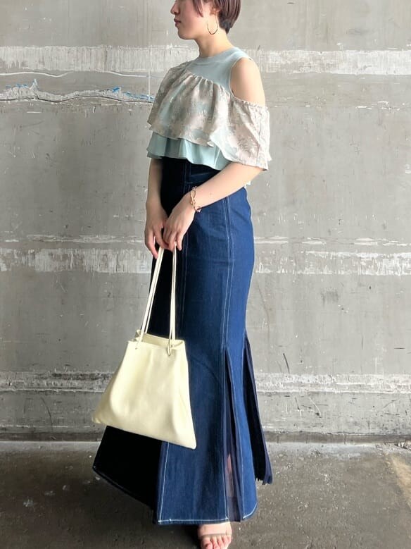 ホワイト系のハンドバッグ、ブルー系のスカート、ベージュ系のサンダルを着用したレディースの春コーディネートの2枚目の写真