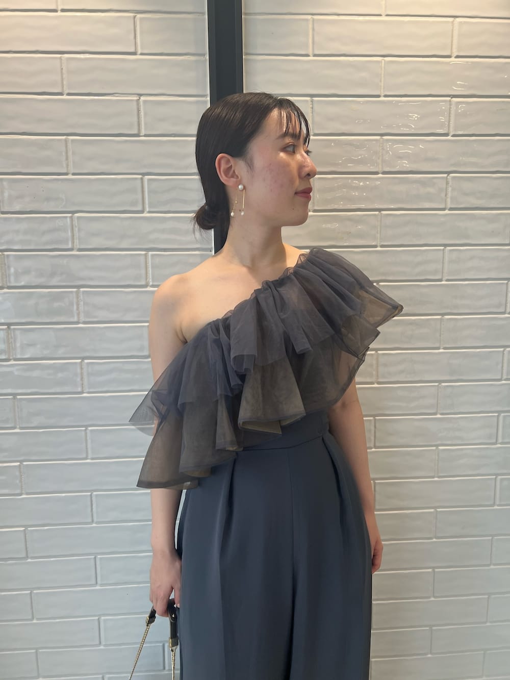 ゴールド系のハンドバッグ、ゴールド系のパンプス、グレー系のパンツドレスを着用したレディースの夏コーディネートの7枚目の写真