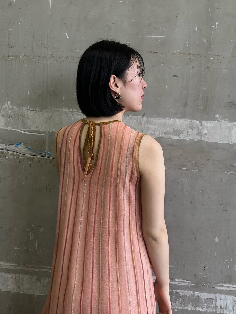 ホワイト系のスニーカー、ベージュ系のハンドバッグ、オレンジ系のワンピースを着用したレディースの春コーディネートの4枚目の写真