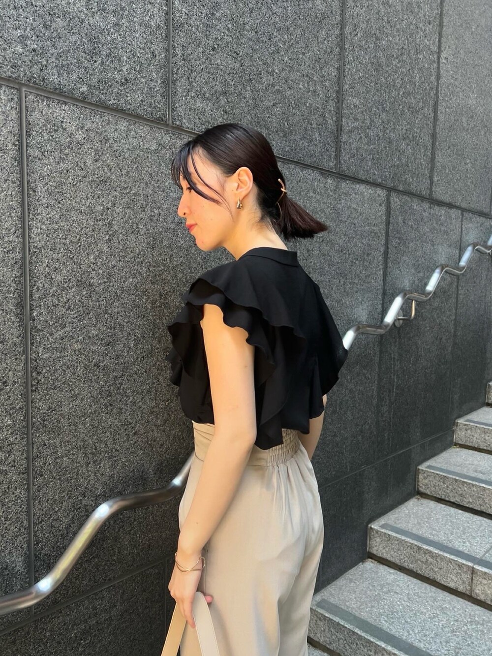 その他のサンダル、ベージュ系のハンドバッグ、ホワイト系のスラックスを着用したレディースの夏コーディネートの4枚目の写真