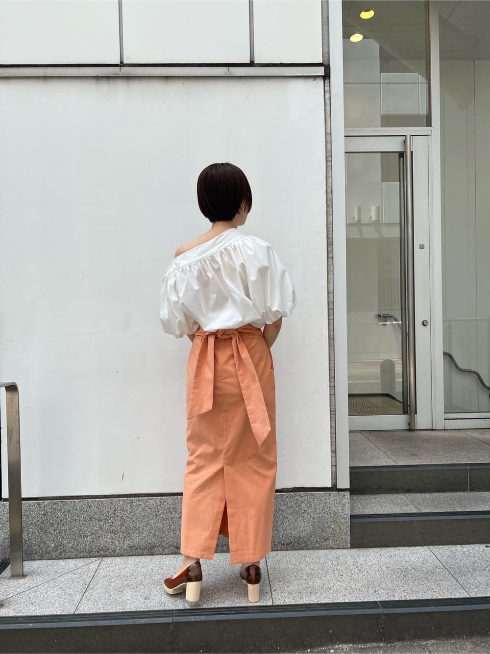 ホワイト系のシャツ/ブラウス、オレンジ系のスカート、ブラウン系のパンプスを着用したレディースの春コーディネートの3枚目の写真