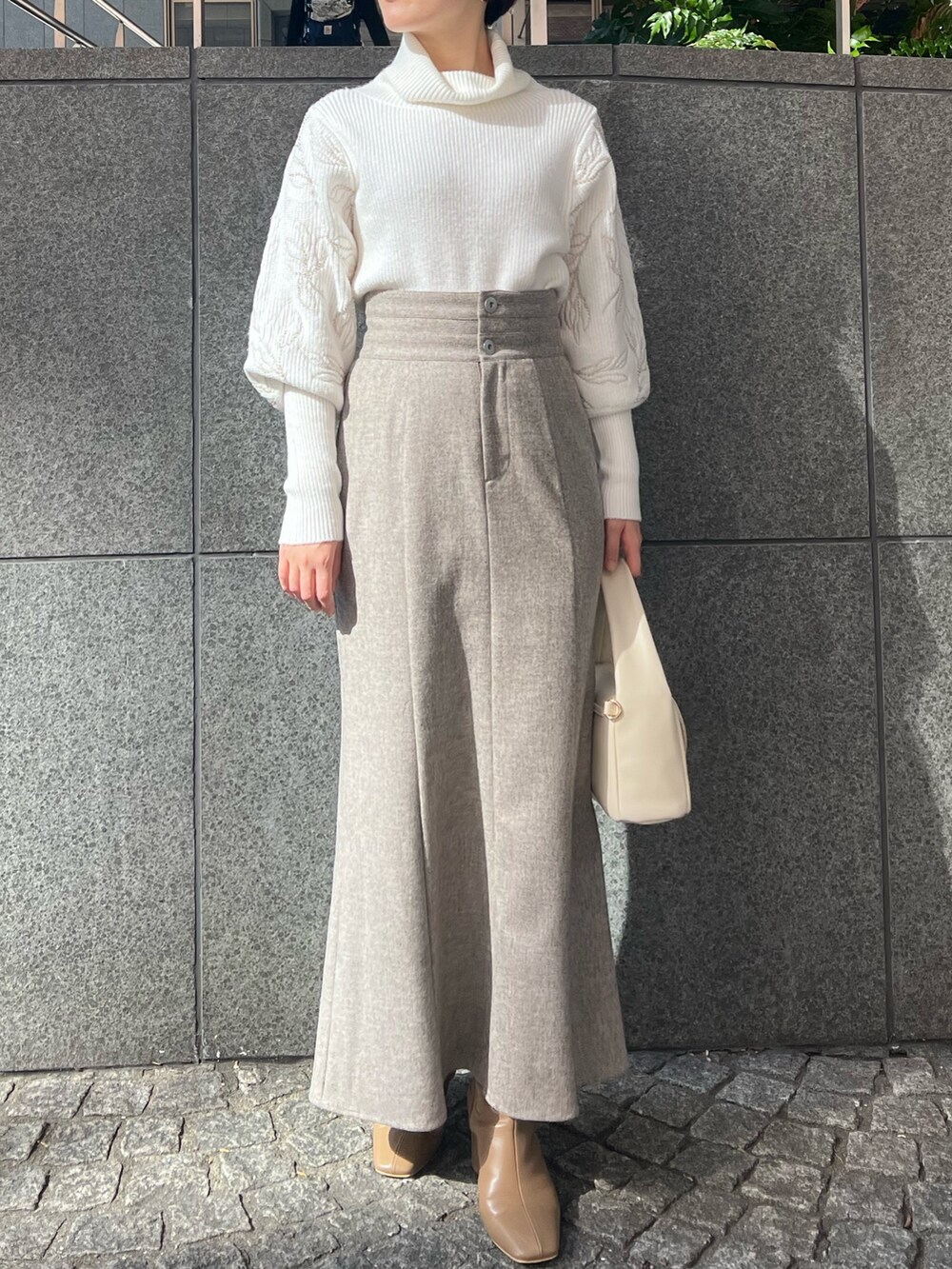 ベージュ系のブーツ、グレー系のスカート、ホワイト系のハンドバッグを着用したレディースの秋コーディネートの6枚目の写真