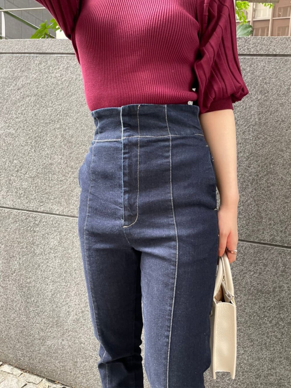 ブラック系のブーツ、レッド系のニット/セーター、ブルー系のデニムパンツを着用したレディースの秋コーディネートの4枚目の写真