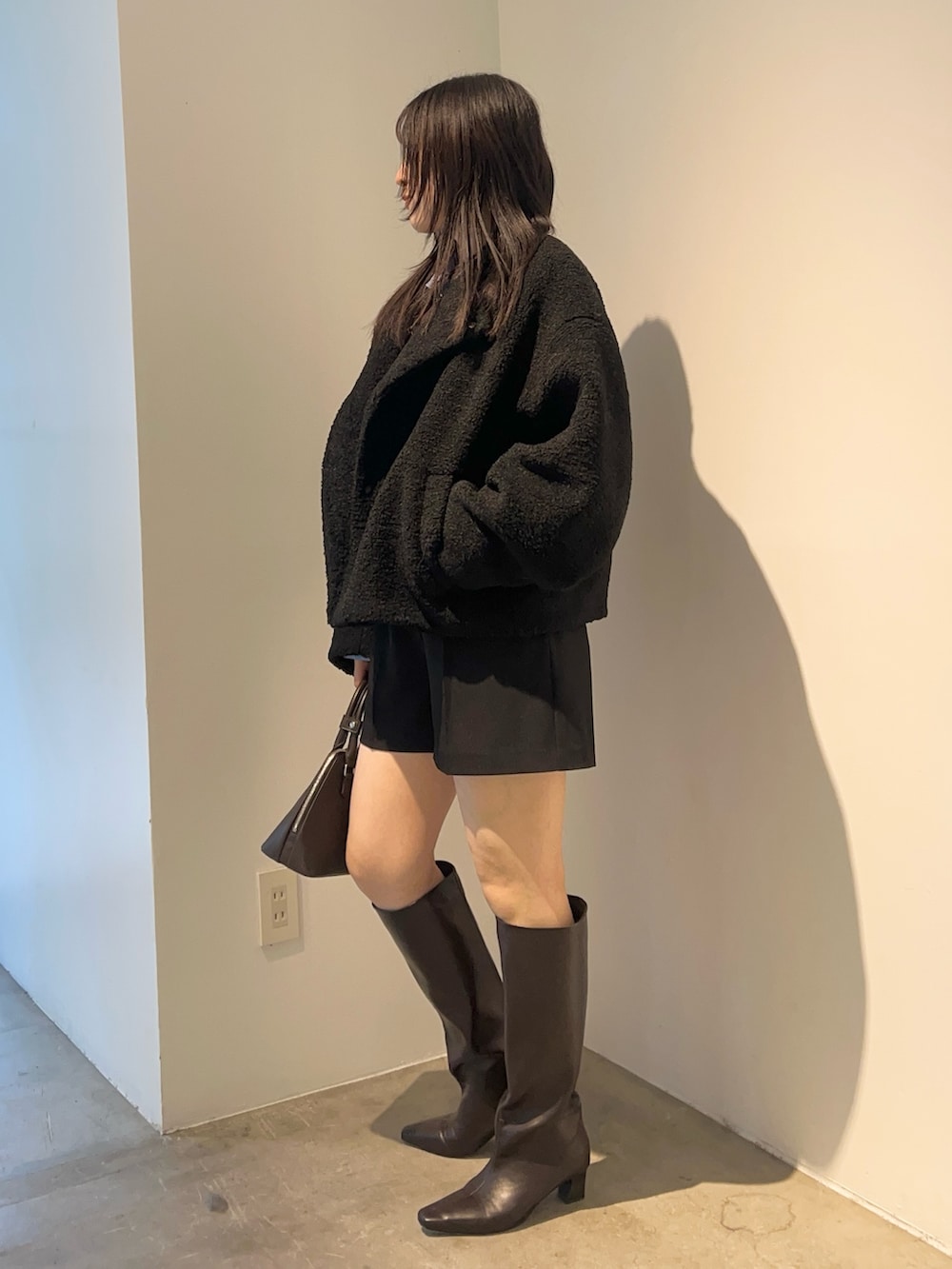 ブラウン系のブーツ、ブラック系のブルゾン、ブラウン系のニット/セーターを着用したレディースの秋コーディネートの2枚目の写真