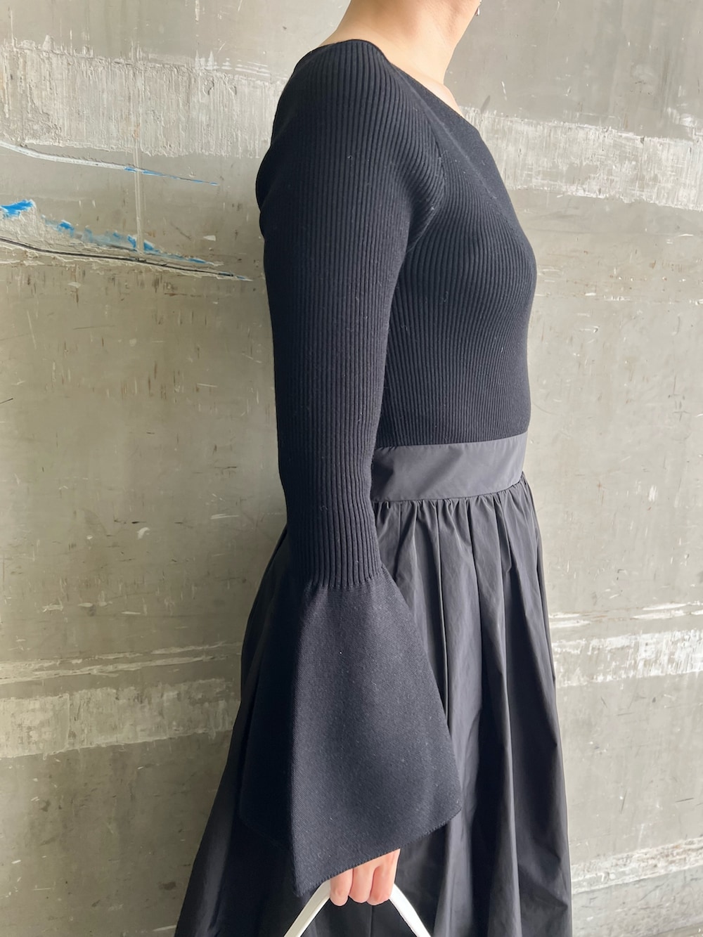 ホワイト系のハンドバッグ、ブラック系のワンピース、ブラック系のパンプスを着用したレディースの秋コーディネートの6枚目の写真