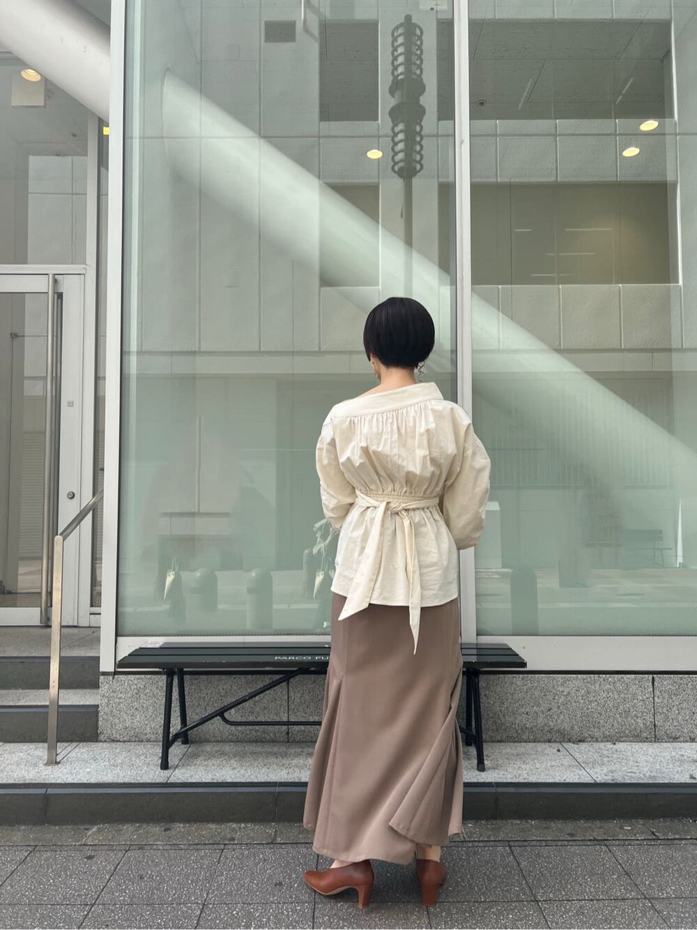 ベージュ系のスカート、ホワイト系のシャツ/ブラウス、ホワイト系のパンプスを着用したレディースの冬コーディネートの7枚目の写真