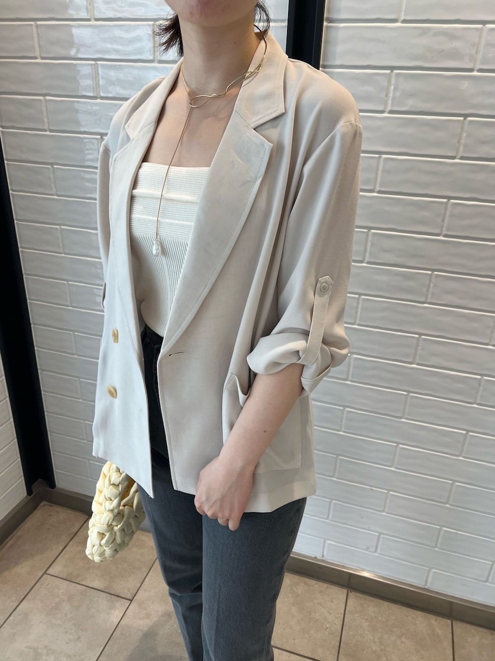 ホワイト系のキャミソール、ブラック系のデニムパンツ、ベージュ系のテーラードジャケットを着用したレディースの夏コーディネートの3枚目の写真