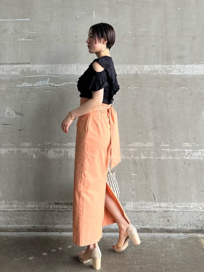 オレンジ系のスカート、その他のパンプス、ブラック系のニット/セーターを着用したレディースの春コーディネートの2枚目の写真