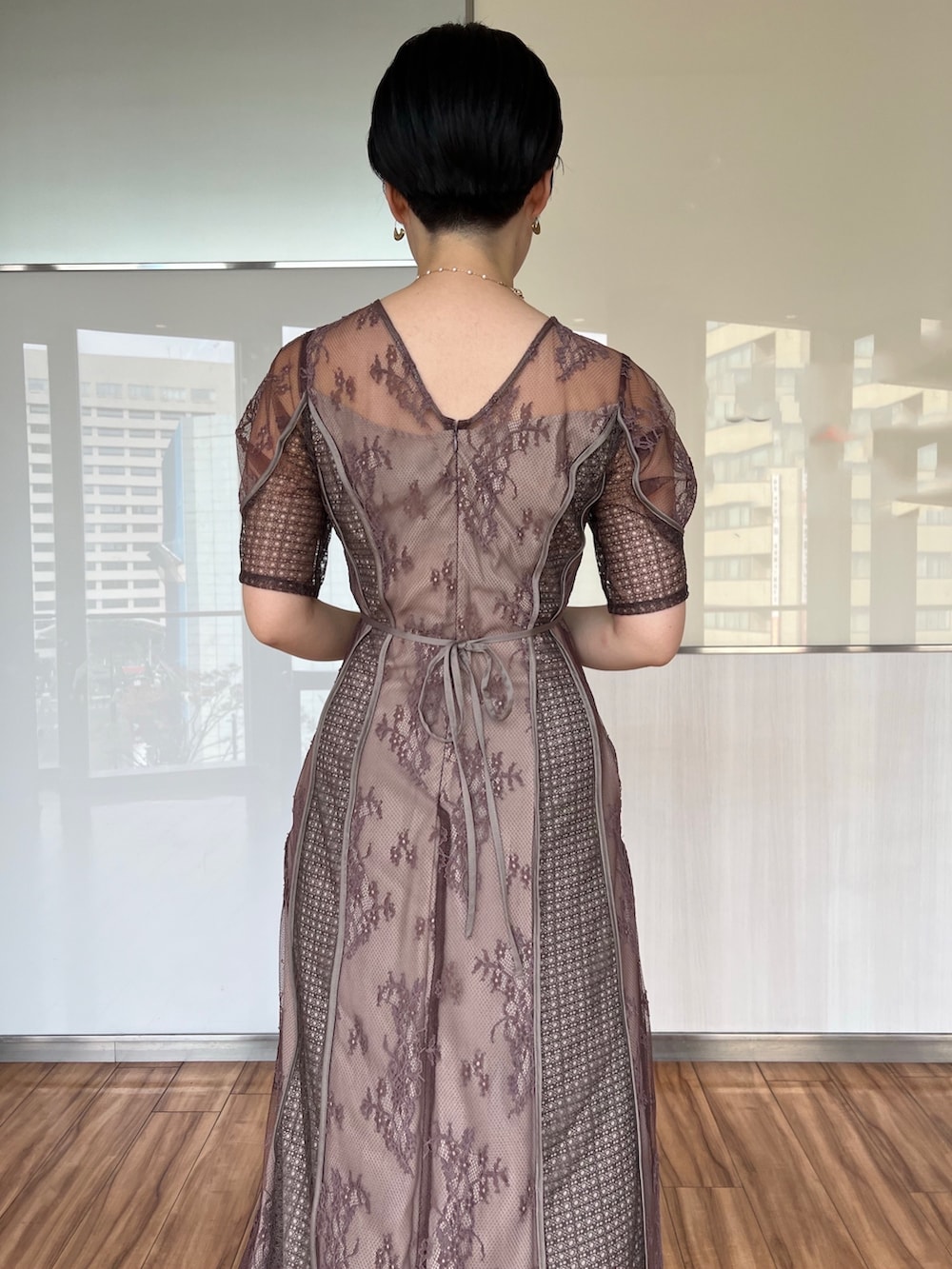 ゴールド系のハンドバッグ、ゴールド系のパンプス、ベージュ系のドレスを着用したレディースの冬コーディネートの3枚目の写真