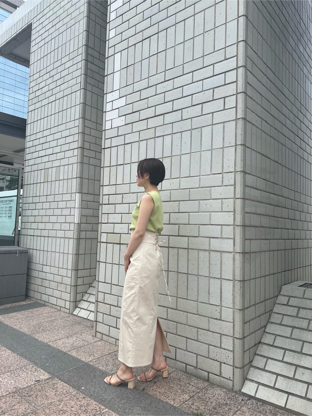 ホワイト系のハンドバッグ、グリーン系のサンダル、ホワイト系のスカートを着用したレディースの春コーディネートの2枚目の写真