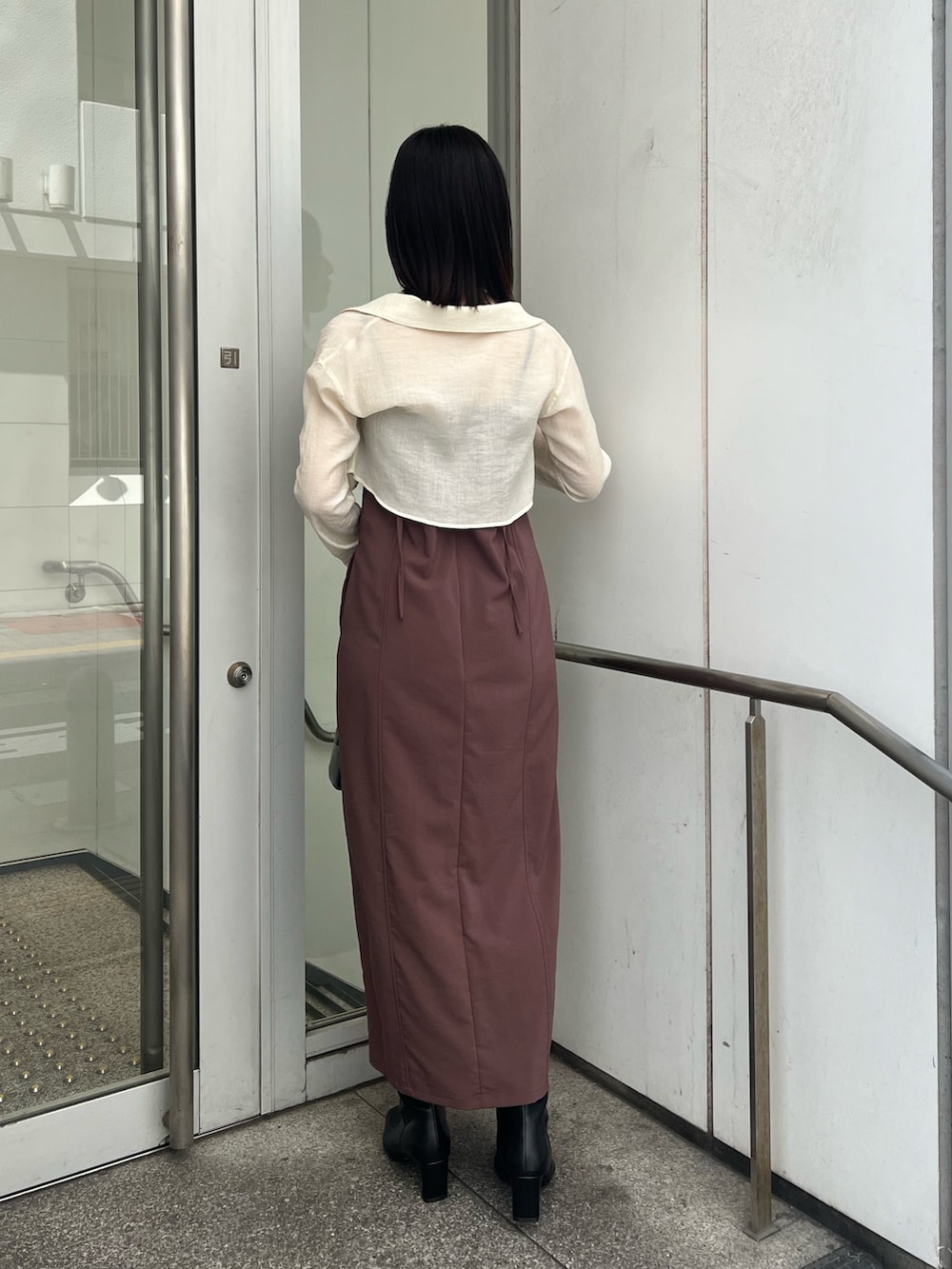 ブラック系のショルダーバッグ、ブラウン系のワンピース、ブラック系のブーツを着用したレディースの秋コーディネートの2枚目の写真