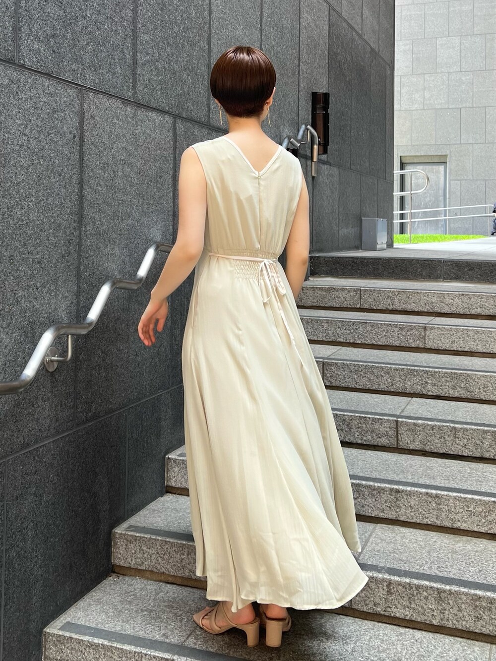 ベージュ系のサンダル、ホワイト系のハンドバッグ、グリーン系のワンピースを着用したレディースの夏コーディネートの2枚目の写真