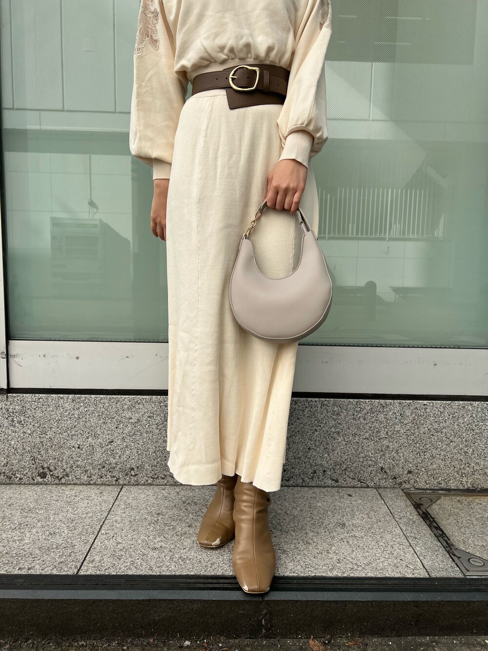 ホワイト系のハンドバッグ、ベージュ系のブーツ、ホワイト系のワンピースを着用したレディースの冬コーディネートの7枚目の写真