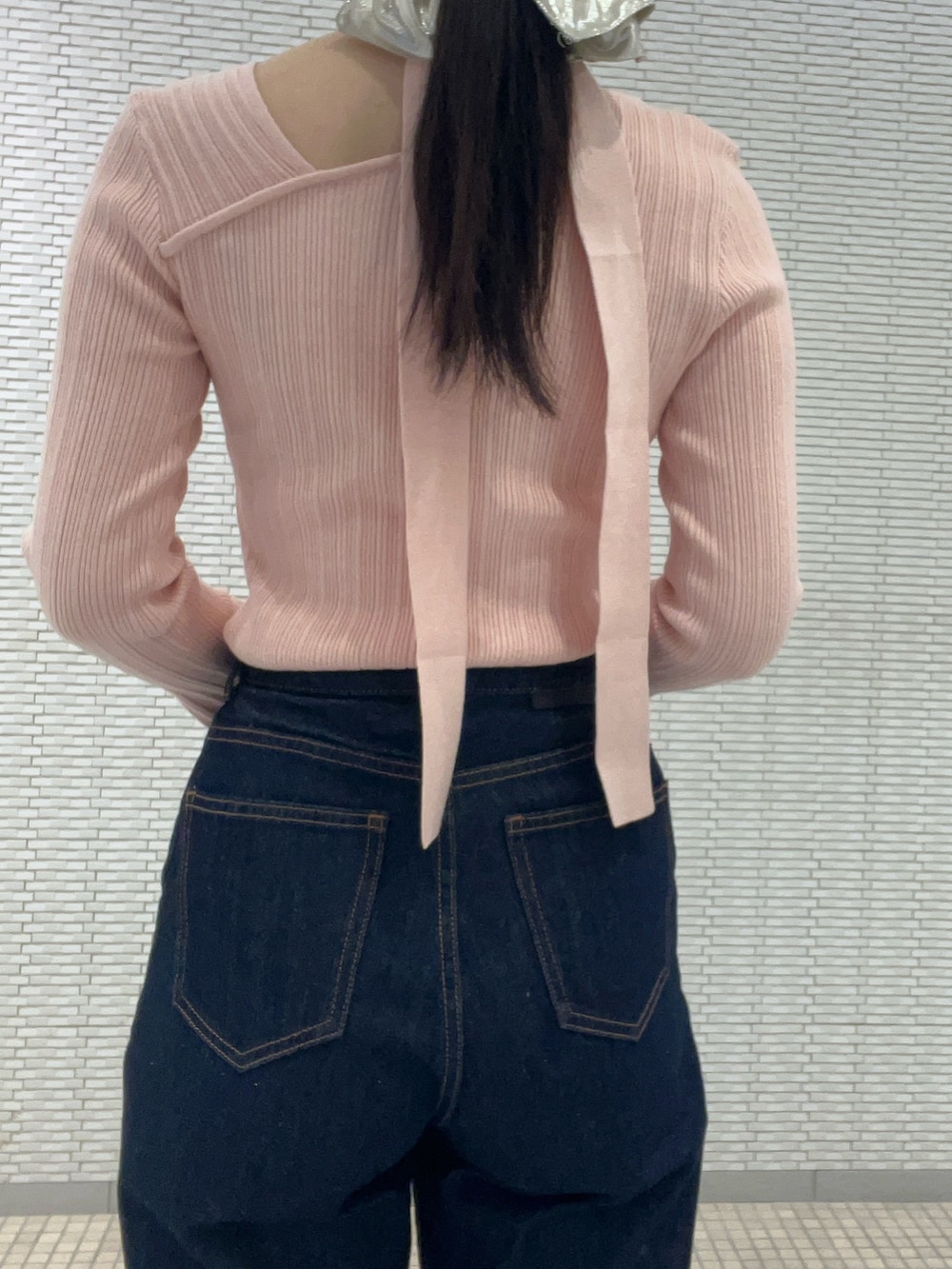 ブルー系のデニムパンツ、ピンク系のニット/セーター、イエロー系のハンドバッグを着用したレディースの冬コーディネートの5枚目の写真