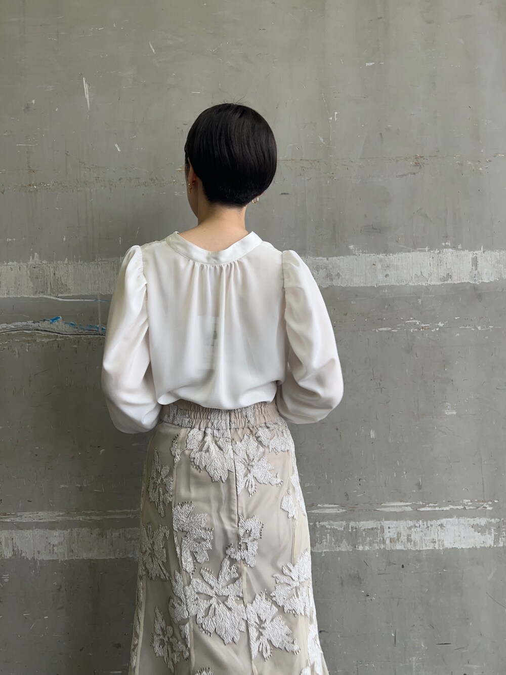 ベージュ系のスカート、ホワイト系のシャツ/ブラウス、ゴールド系のピアス(両耳用)を着用したレディースの秋コーディネートの4枚目の写真