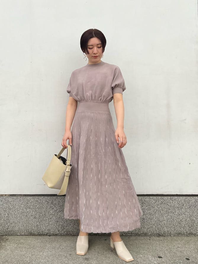 ホワイト系のノーカラーコート、グレー系のワンピース、ホワイト系のサンダルを着用したレディースの冬コーディネートの2枚目の写真