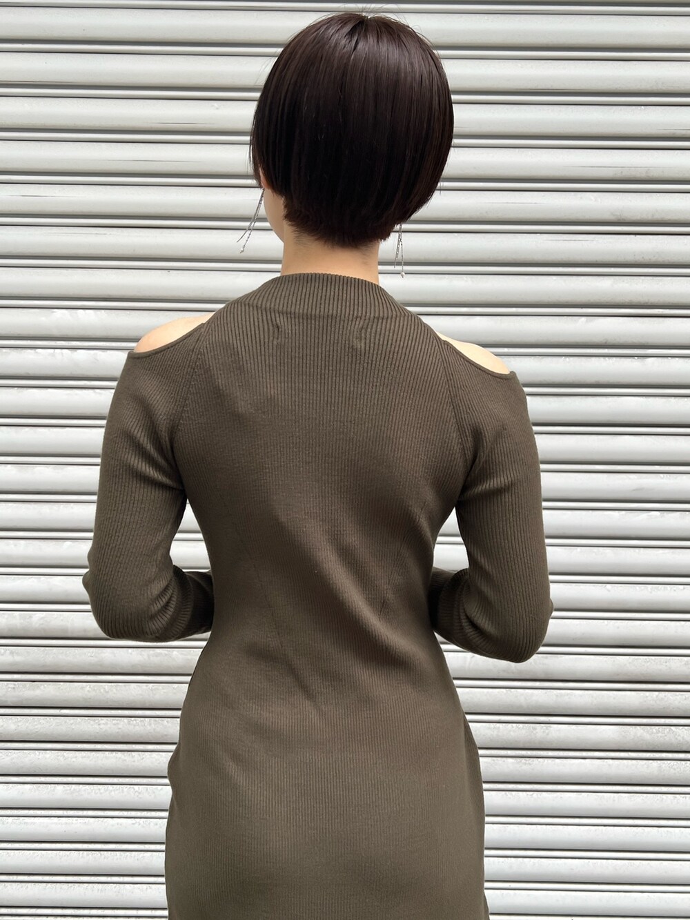 レッド系のブーツ、ブラック系のハンドバッグ、グリーン系のワンピースを着用したレディースの冬コーディネートの6枚目の写真