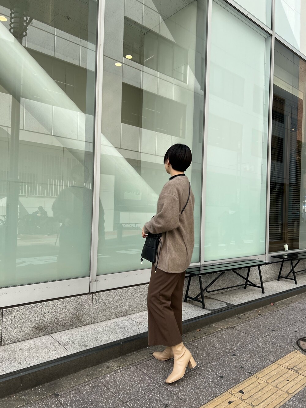 ブラック系のハンドバッグ、ベージュ系のブーツ、ベージュ系のカーディガン/ボレロを着用したレディースの秋コーディネートの2枚目の写真