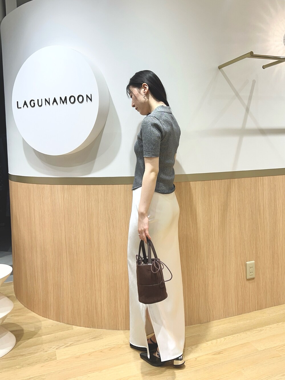 グレー系のニット/セーター、ブラック系のパンプス、ブラウン系のハンドバッグを着用したレディースの春コーディネートの3枚目の写真